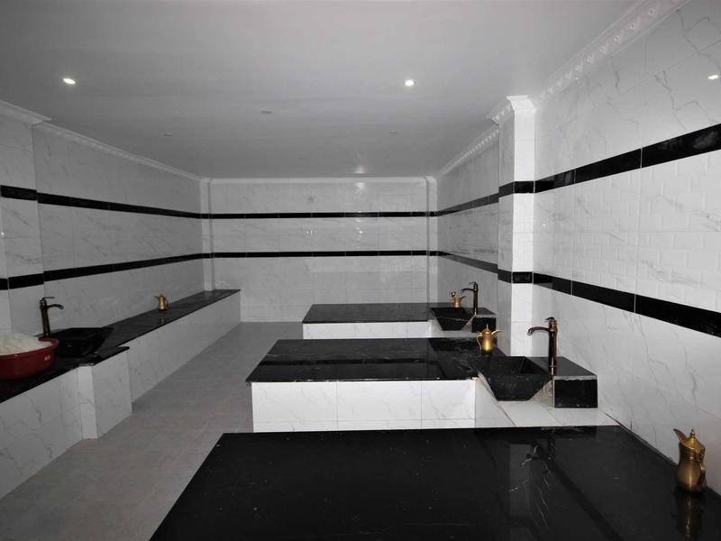 Minimalistischer Raum mit weißen Fliesen, schwarzen Streifen und schwarzen Waschbecken.