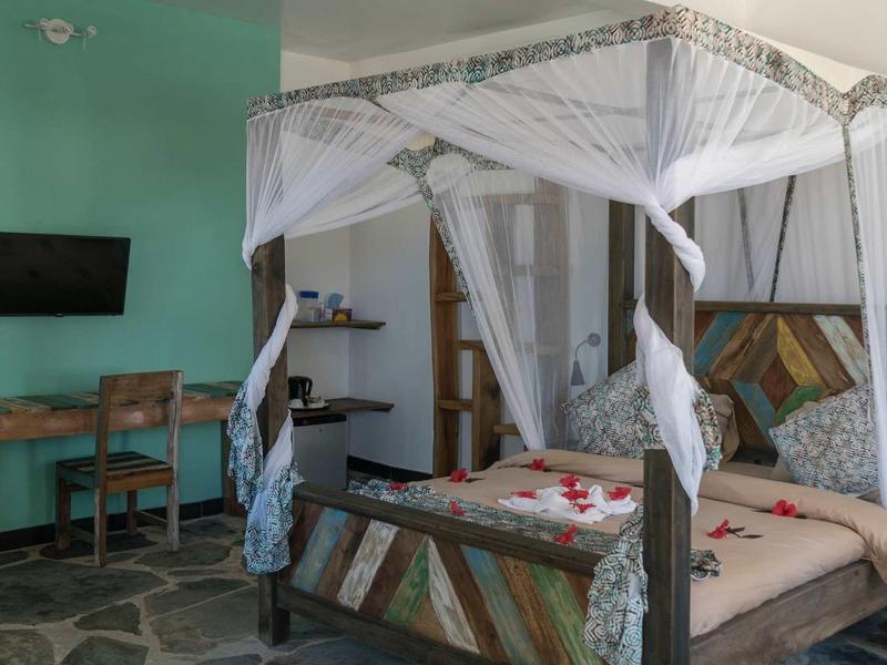 Helles Schlafzimmer mit Vierpfostenbett, Holzmöbeln und türkisfarbenen Wänden.