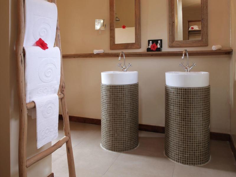 Modernes Badezimmer mit zwei runden Waschbecken, zwei Spiegeln und einem Holztuchhalter mit Handtüchern.