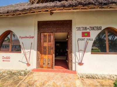 Edificio bianco tradizionale con supporti in legno e scritte rosse, circondato dalla natura.