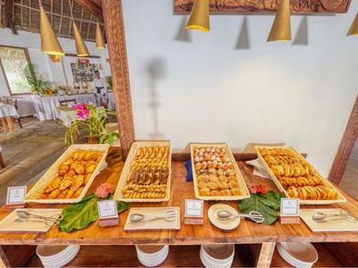 Ein großes Buffet mit verschiedenen warmen Gerichten in einem hellen Restaurant mit Holztischen.