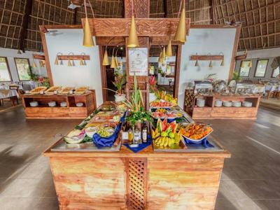 Großes Buffet mit frischem Obst und Gemüse in offenem, lichtdurchflutetem Raum mit Holzboden und -dach.