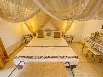 Gemütliches Schlafzimmer mit Doppelbett, weißem Mobiliar, gelben Vorhängen und Baldachin.