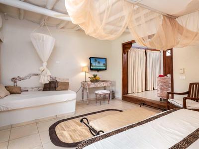 Helles Schlafzimmer mit weißen Möbeln, Holzmöbeln, Teppich und Netzvorhängen an der Decke.