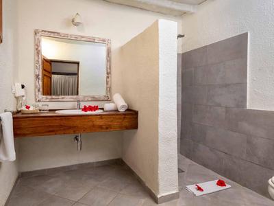 Helles Bad mit Holzwaschtisch, großem Spiegel, grauen Fliesen und Dusche mit halber Wand.