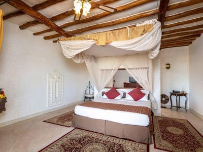 Gemütliches Schlafzimmer mit Himmelbett, Holzbalkendecke, Teppichen und warmen Farbakzenten.