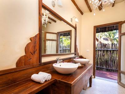 Badezimmer mit großem Holzwaschtisch, rundem Waschbecken und offener Tür zu einem Balkon.