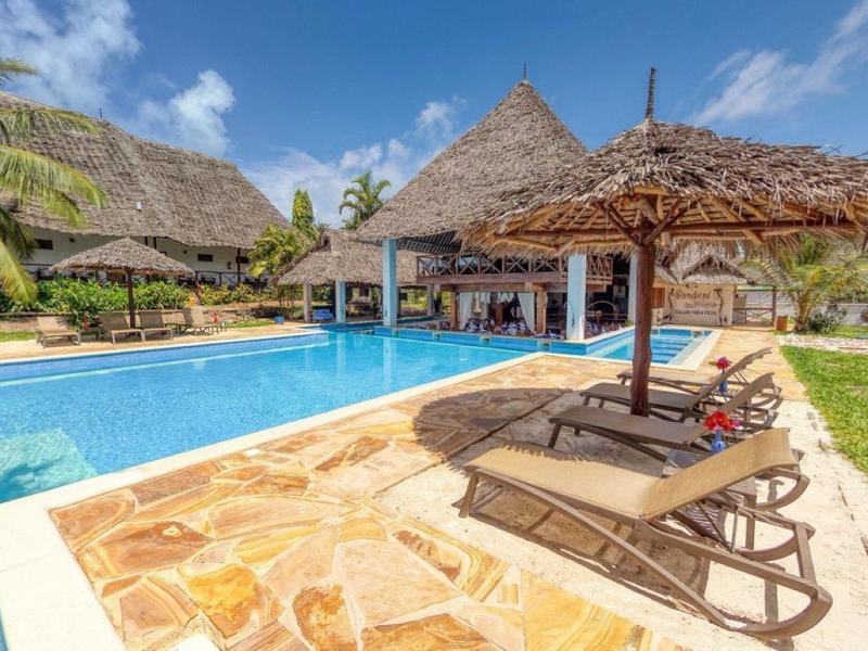 Overdekte zandbak met verschillende kleurrijke speelhuisjes en glijbanen.