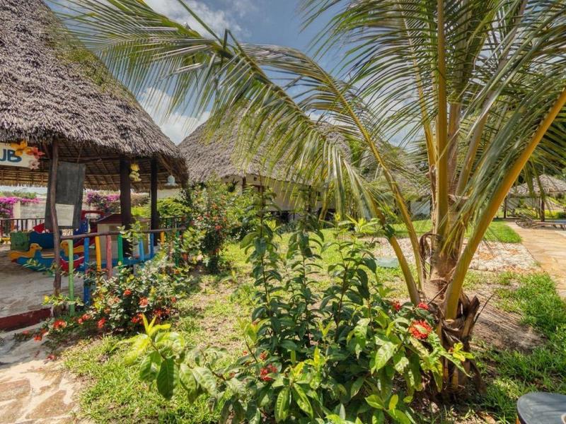 Gezellige open bar met rieten dak en zwembad in tropische hotelomgeving.