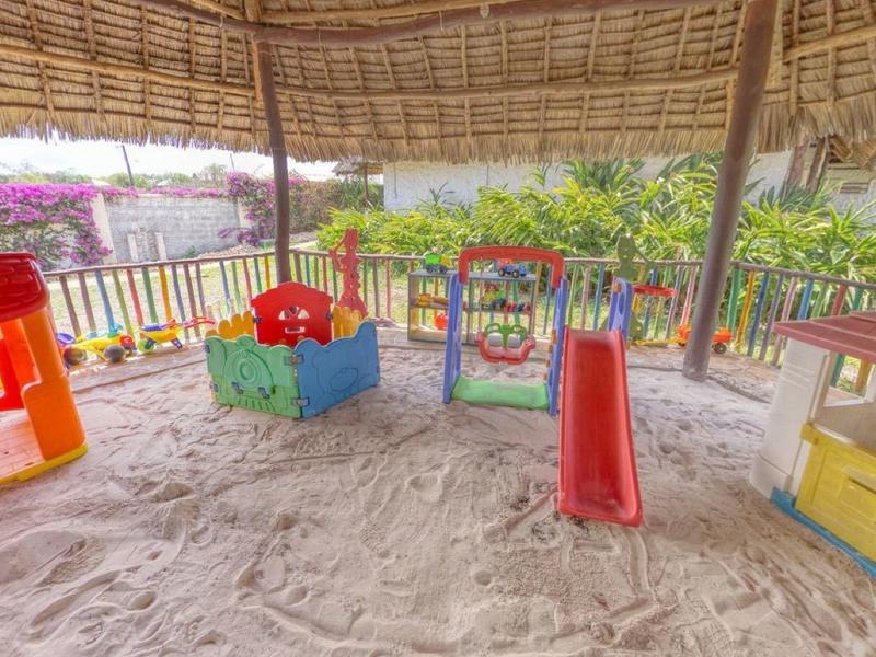 Overdekte zandbak met verschillende kleurrijke speelhuisjes en glijbanen.