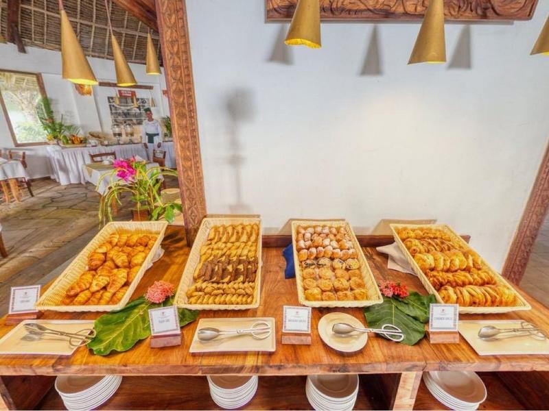 Buffet met verschillende broodsoorten en smeersels in een helder restaurant met houten vloeren.