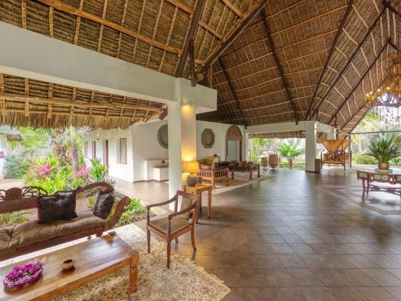 Ruime open lodge met houten dak, stoelen en uitzicht op de natuur.