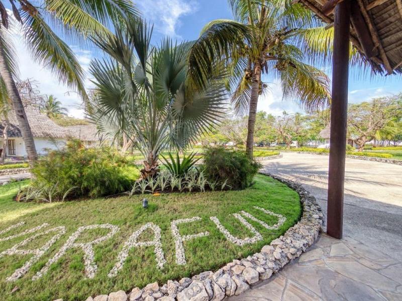 Tropisch hotelgebied met palmbomen en een pad onder een rieten parasol.