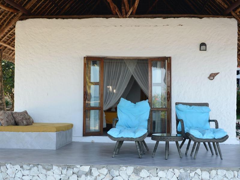 Gezellig terras met twee blauwe stoelen en een kleine tafel voor een deur met gordijnen.