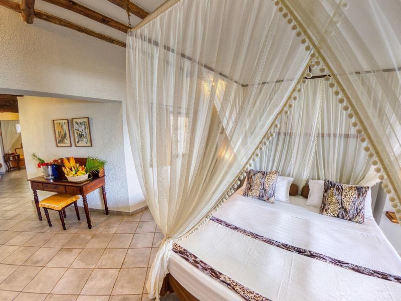 Elegant hotelkamer met hemelbed, dagbed, bureau en stijlvolle decoratie.