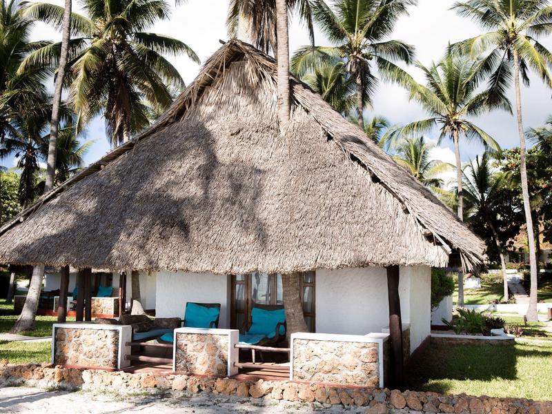 Traditioneel rieten hutje omgeven door palmbomen in een tropisch hotel.