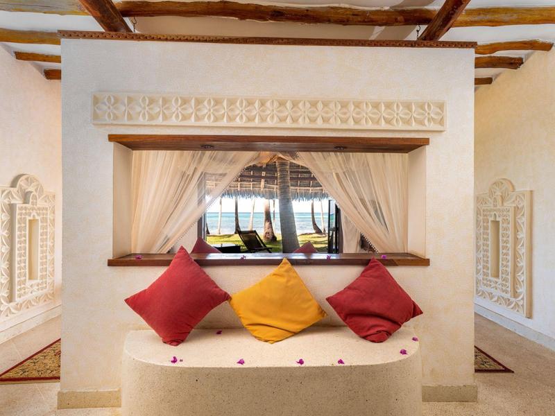 Gezellig bankje met witte gordijnen en kleurrijke kussens voor een groot raam.