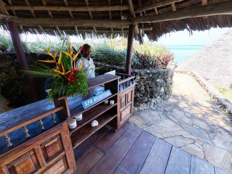 Open hut met rustiek houten interieur en uitzicht op het strand en de zee.