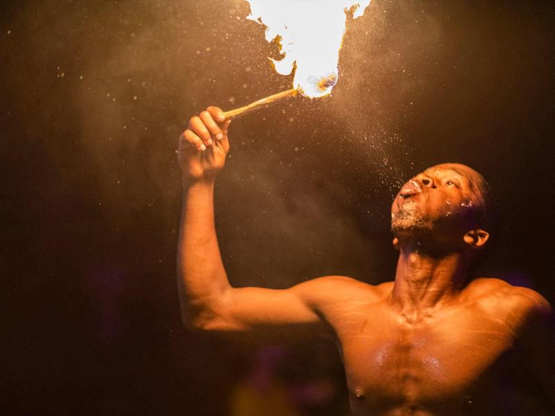 Een man voert een vuurspektakel uit met een brandende fakkel in de nacht.