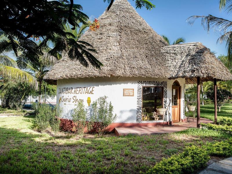 Rond huis met rieten dak in een groene tuin bij zonlicht.