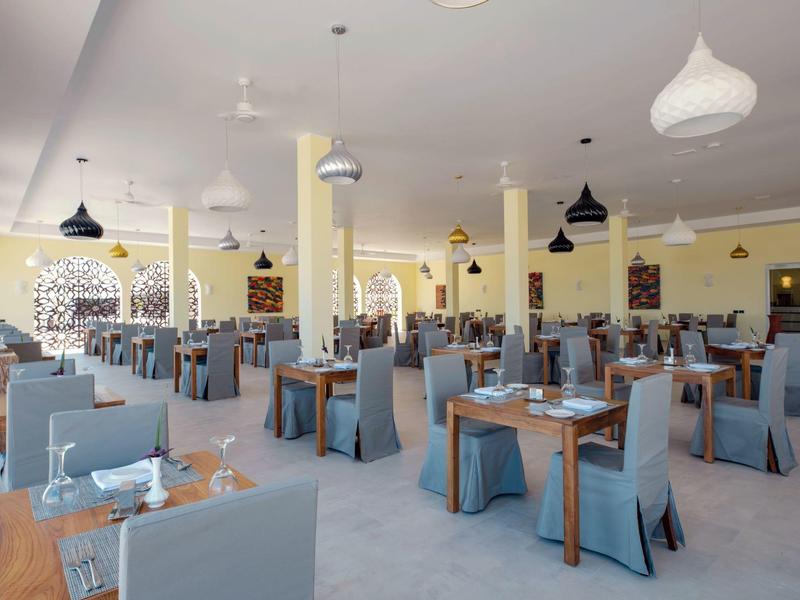 Grote, lichte eetzaal met blauwe stoelen en houten tafels in het hotelrestaurant.