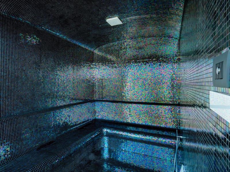 Interieur van een sauna met blauwe tegels en houten banken langs de muren.