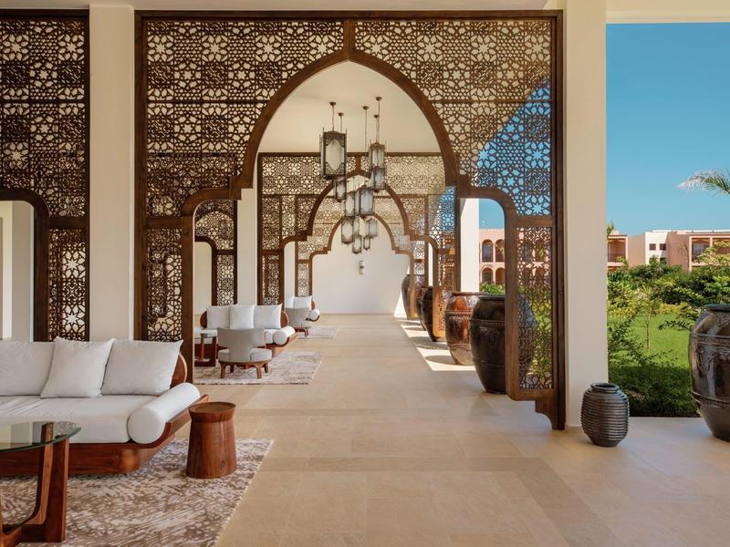 Uitzicht op een elegante hotelgang met sierlijke houtsnijwerk en comfortabele zithoeken.