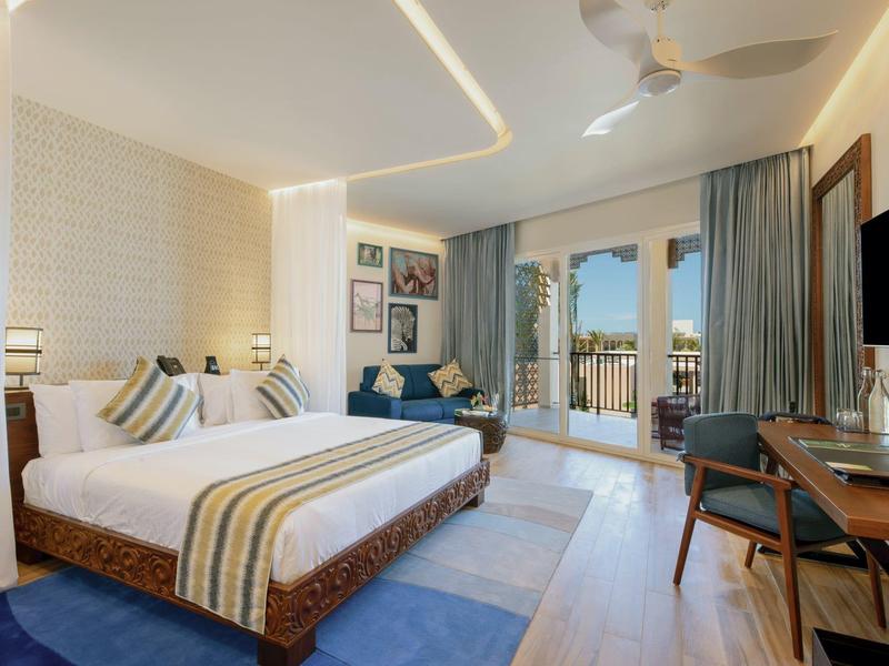 Moderne hotelkamer met groot bed, balkon en elegant interieur.