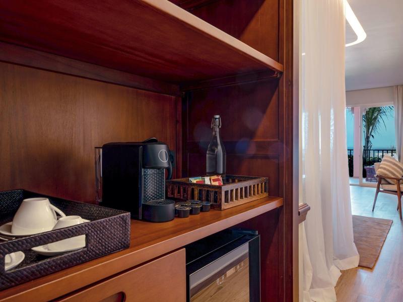 Hotelkamer met thee- en koffiestation op houten plank en uitzicht op woonruimte.