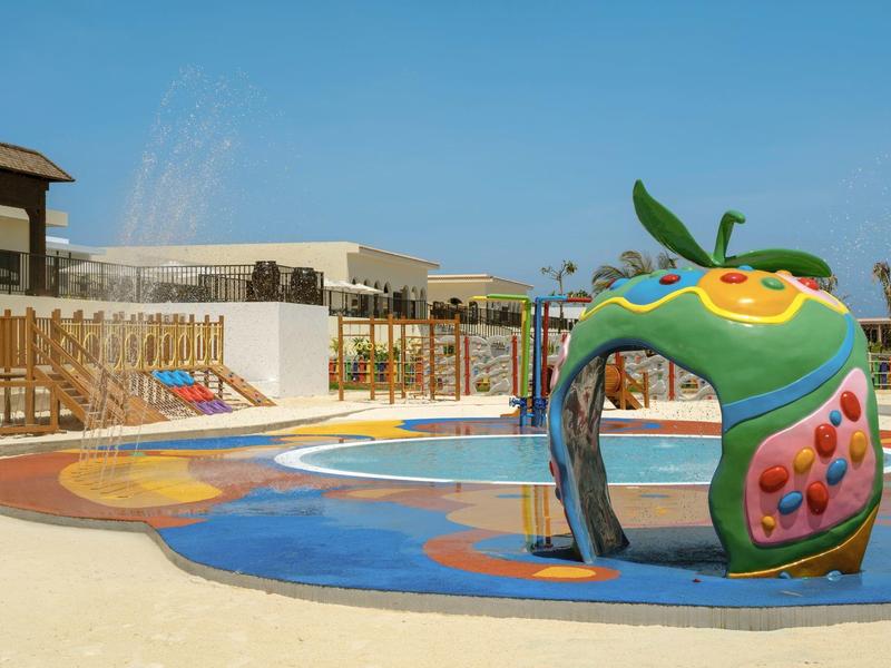 Kleurrijke waterspeelplaats met slangenglijbaan en nevelsproeiers buiten bij een vakantieoord.