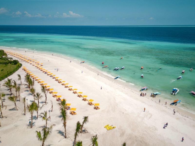 Breit wit zandstrand met gele parasols en turquoise water bij het hotelresort.