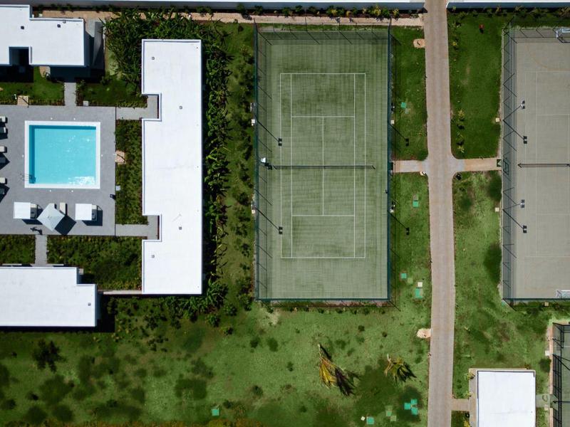 Luchtfoto van een hotelgebied met zwembad, tennisbanen en verharde paden.