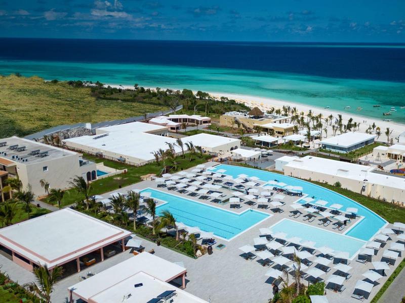 Luxe resort met groot zwembad en uitzicht op wit zandstrand en blauwe zee.