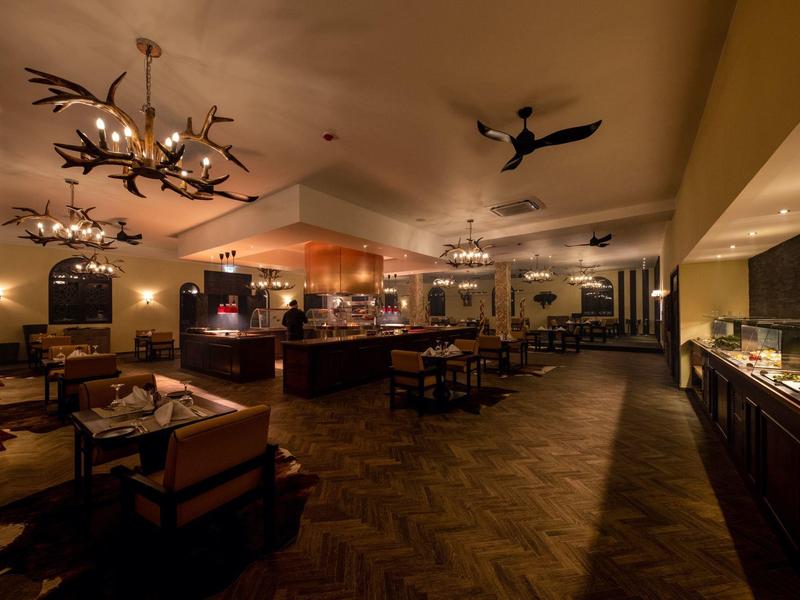 Gezellig restaurant met warm licht, houten meubels en geweilampen aan het plafond.