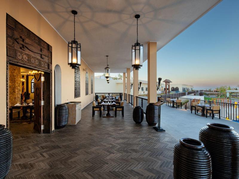 Groot terras met tafels, stoelen en decoratieve vazen met uitzicht op de stad.