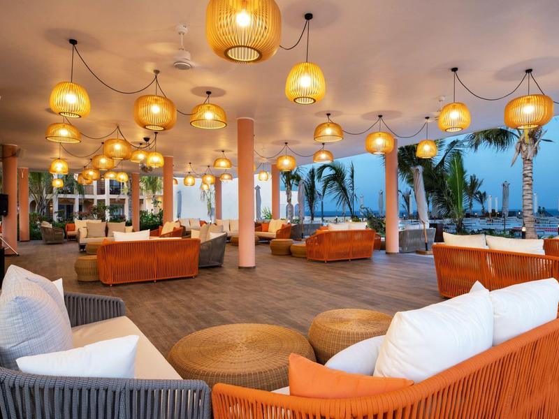 Open hotel lounge met comfortabele banken en lantaarnverlichting in de avond.