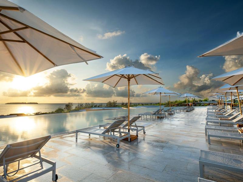 Luxe zwembad met ligstoelen en parasols bij zonsondergang.