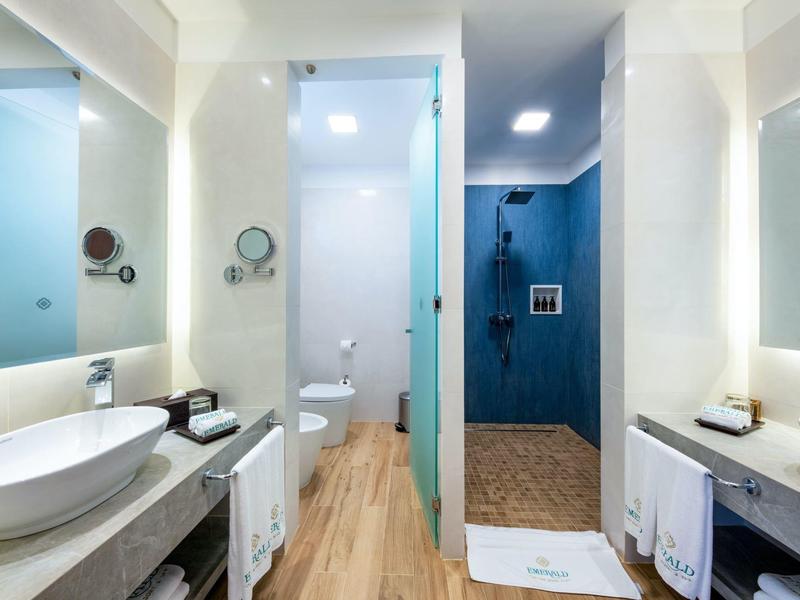 Moderne badkamer met witte wastafels, grote spiegels en houten vloer in een hotelkamer.