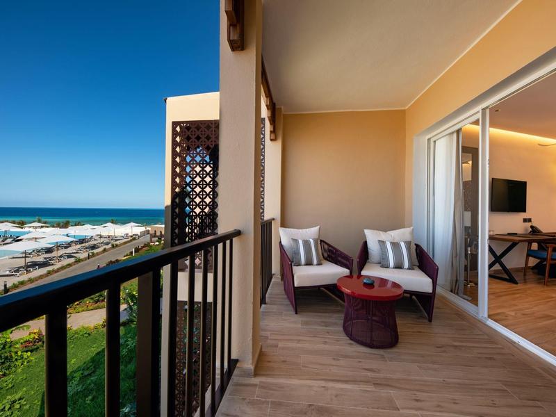 Balkon met fauteuils en zeezicht, grenzend aan een woonruimte met eettafel.