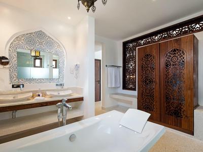 Moderne Badezimmereinrichtung mit freistehender Badewanne, Holzwaschbecken und kunstvoll verziertem, dunklem Holztür-Element.