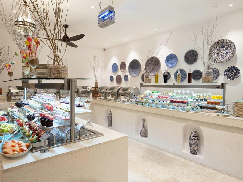 Bufé luminoso con diversas comidas y decoración de platos artísticos en sala moderna.