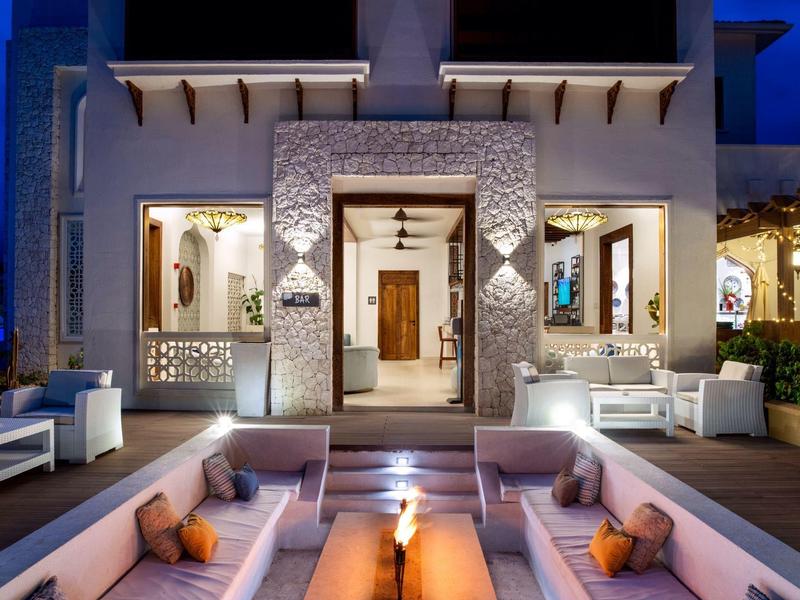 Área exterior lujosa de un hotel con asientos y cálida iluminación nocturna.