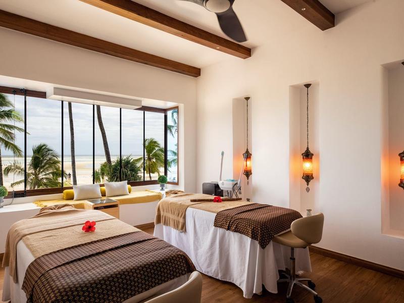 Sala de spa luminosa con dos camillas de masaje y vista al mar a través de grandes ventanales.