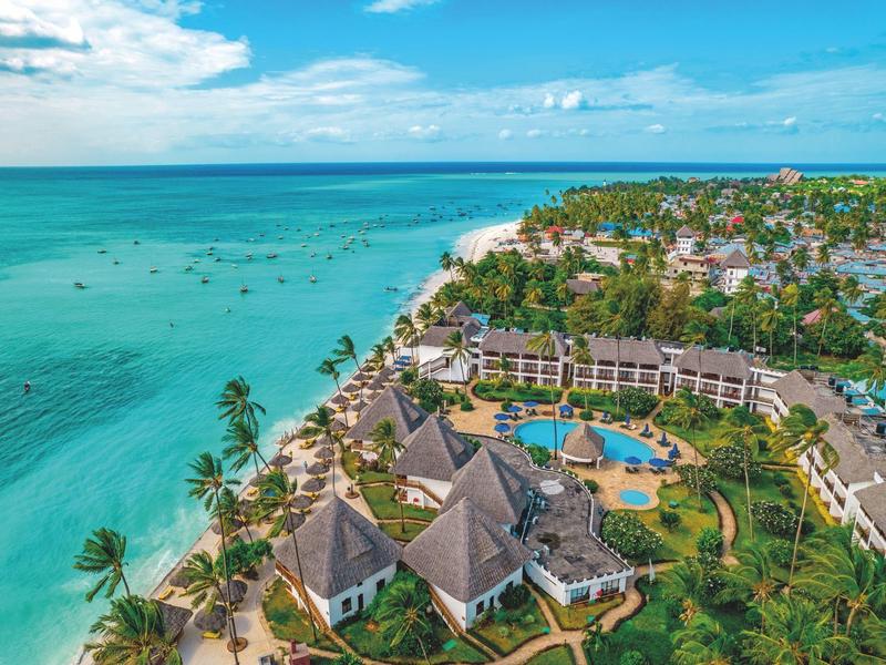 Luxe strandresort met zwembaden en palmbomen langs de turquoise kustlijn.