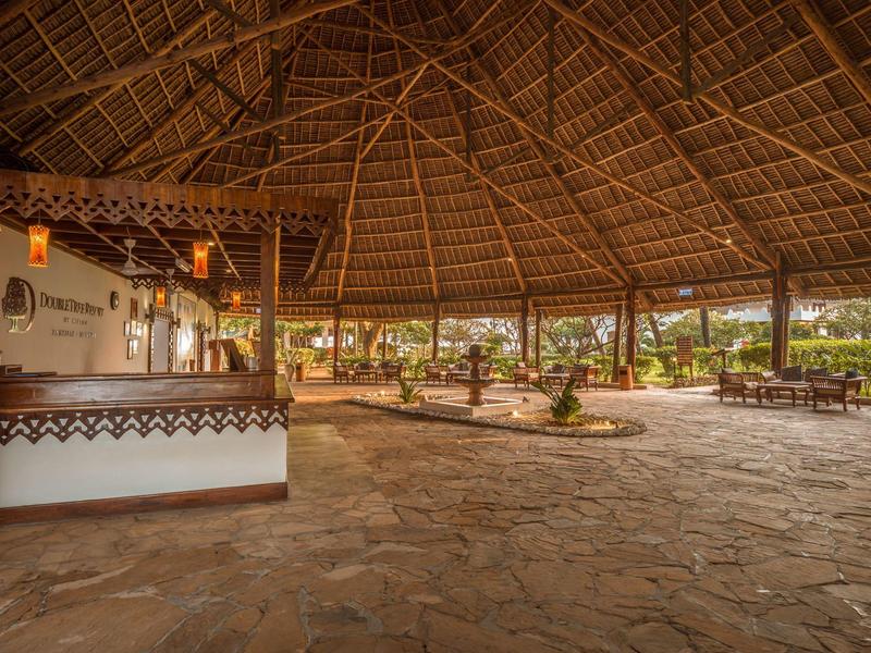 Grote overdekte ruimte met open houten dak en stenen vloer in een vakantieomgeving.