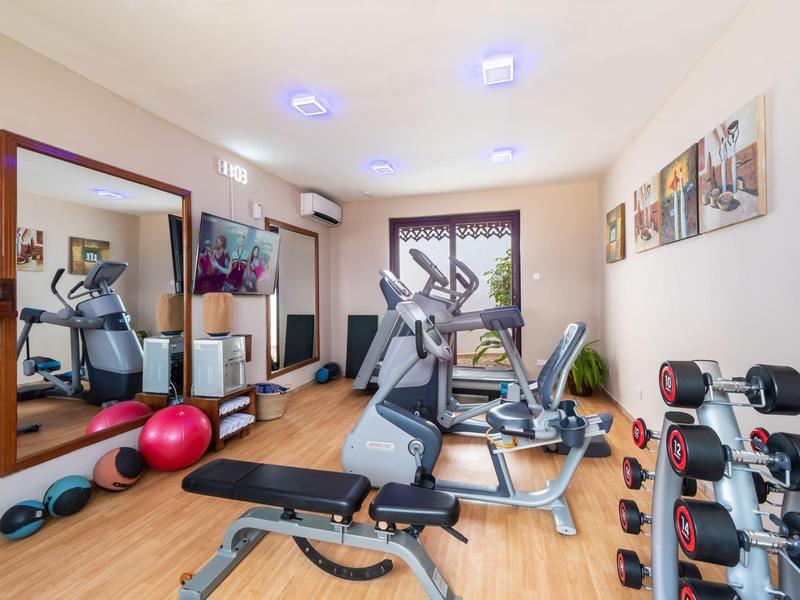 Moderne fitnessruimte met trainingsapparatuur, halters, fitnessbal en spiegelwand.