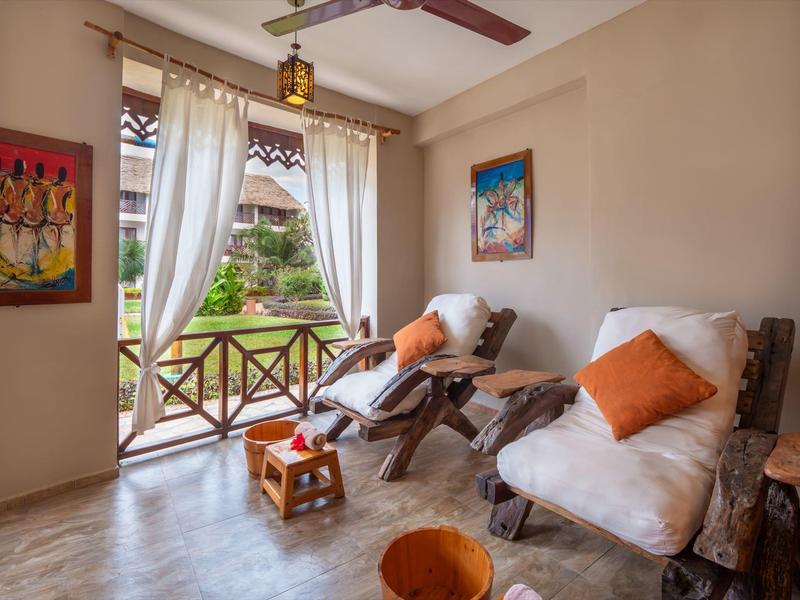 Gezellig balkon met witte stoelen, oranje kussens en uitzicht op tuin en naburige gebouwen.