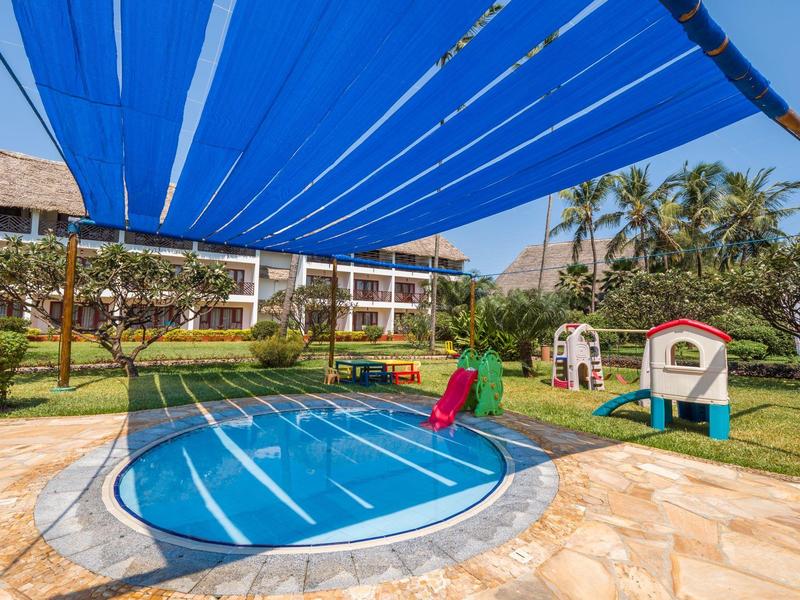 Klein rond zwembad met blauwe afdekking in een hotel tuin met een speelplaats.