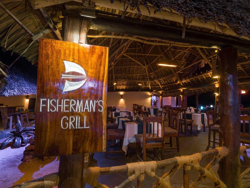 Open restaurant aan het strand met houten bord 'Fisherman's Grill' en gezellige verlichting.