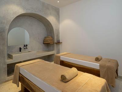 Dwa łóżka do zabiegów w spokojnym, minimalistycznym spa o neutralnej kolorystyce.